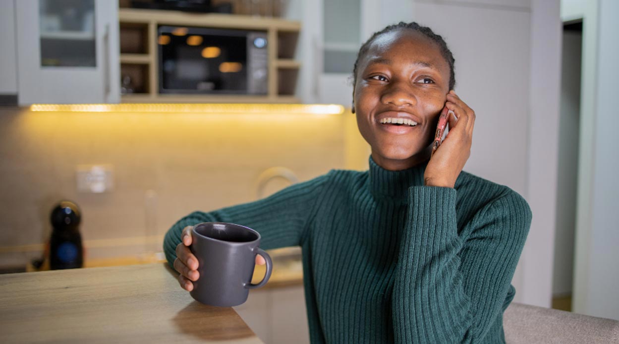 a woman holding a cup talking on her mobile phone